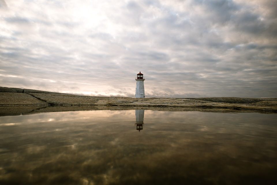 Lighthouse reflected in coastal water at Peggys Cove, Canada
